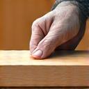 Icon representing a craftsman's hand holding a perfectly planed wooden block, signifying quality.